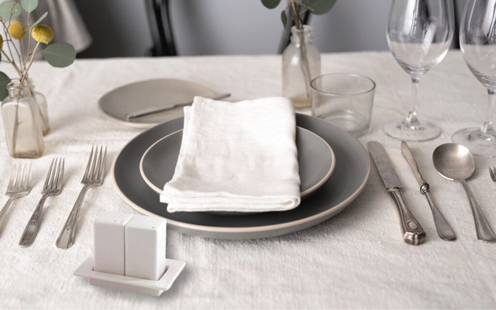 Porcelain salt and pepper shaker on the tray on a table for a dinner 1
